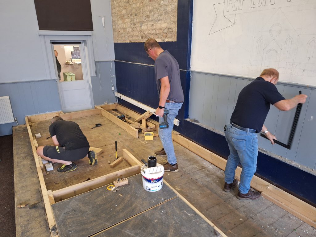 Laying out the new baptistry area in the new workshop area while Bob measures up for the mural