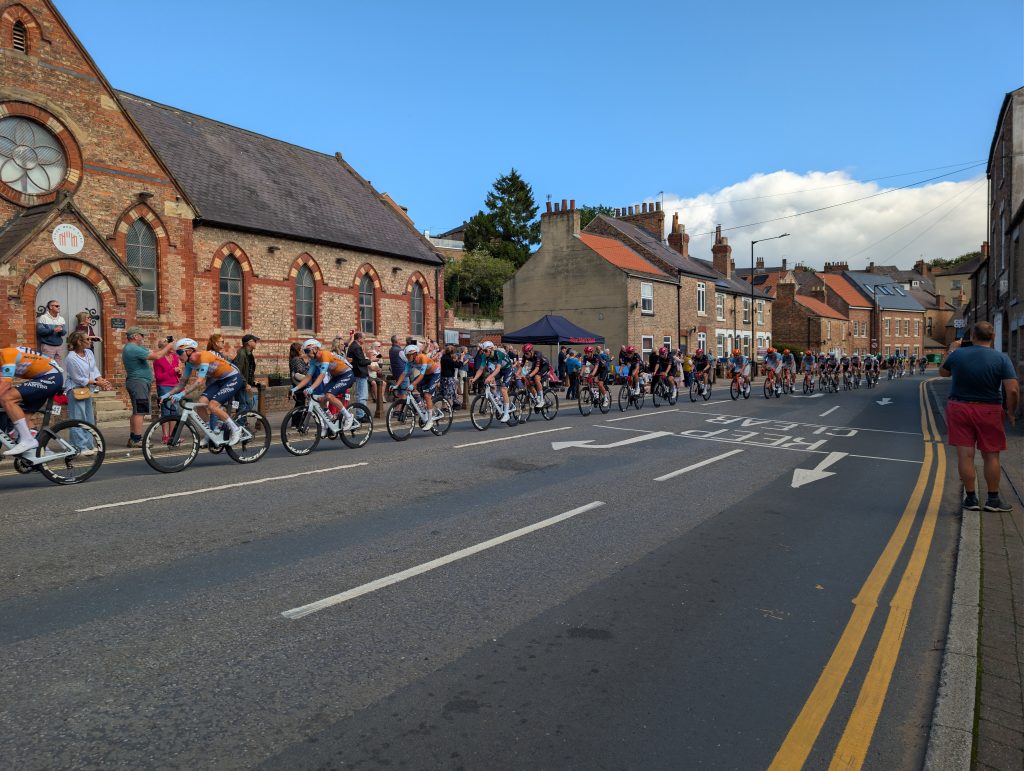The large peloton crosses in front